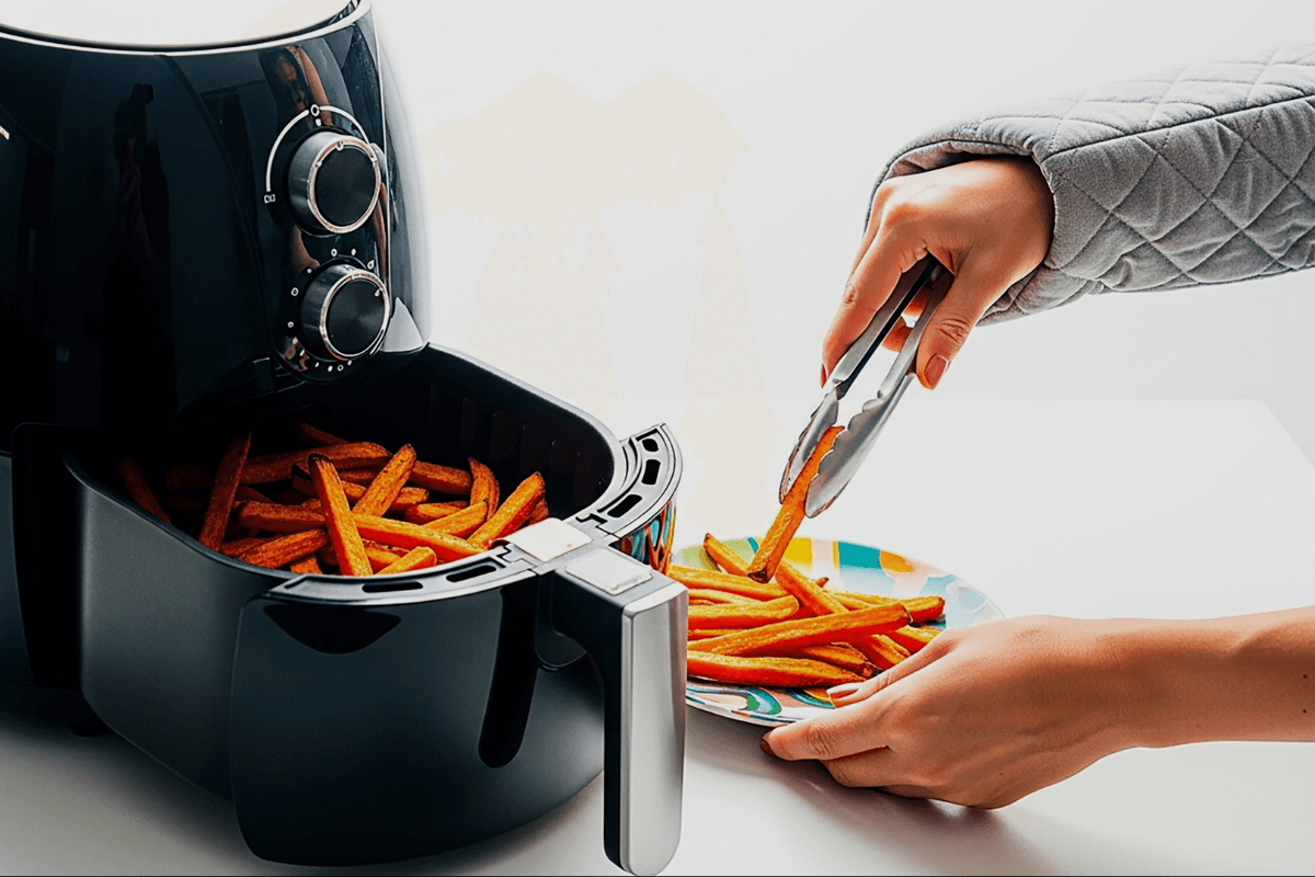 Pessoa servindo batatas fritas de uma air fryer preta usando um pegador de metal, exemplificando o uso correto ao evitar o que não pode ir na airfryer.