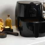 Fritadeira preta fechada sobre a bancada branca ao lado de batatas fritas, ilustrando o artigo sobre qual é a air fryer mais vendida.