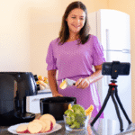 Mulher gravando preparo de batatas e brócolis na airfryer, demonstrando na prática se o eletrodoméstico vale a pena no dia a dia.